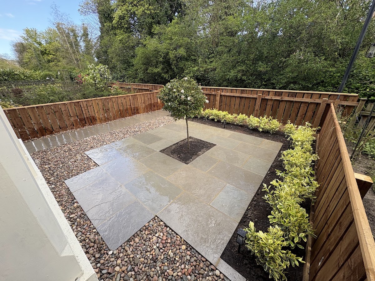 Sandstone patio with a central ornamental tree, cobble borders and fresh planting